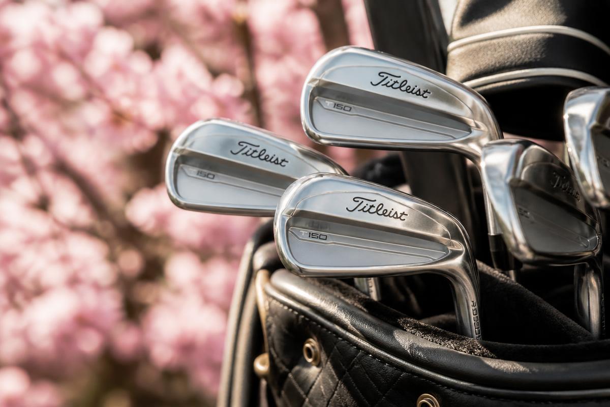 Golf irons in a bag beside pink blossom